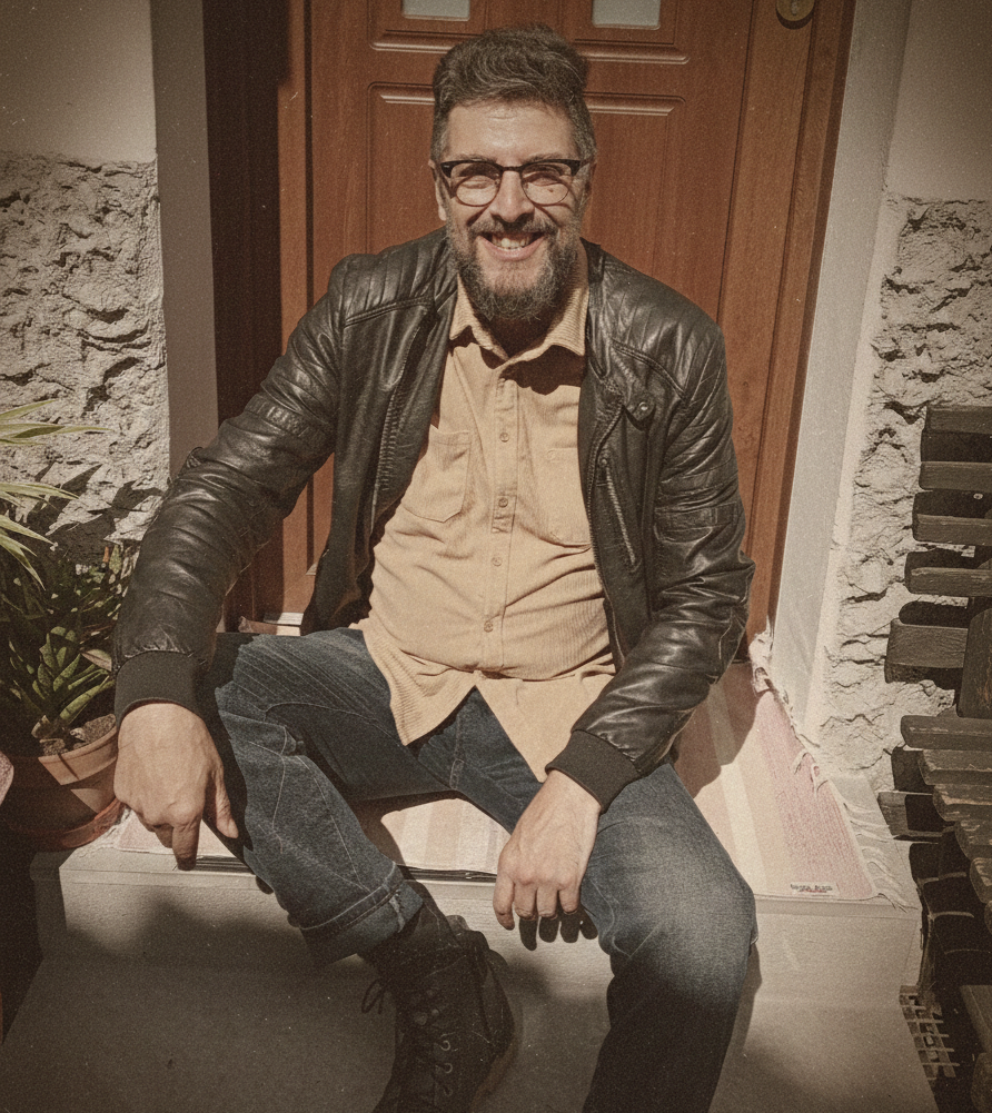 La foto ritrae l'autore sedito, sorridente, sugli scalini davanti alla porta di ingresso della sua casa. Pettinatura lontanamente alla mohicana, occhiali ed una folta barba. Indossa una giacchetta di pelle nera sopra ad una camicia in velluto beige, jeans e scarponcini.